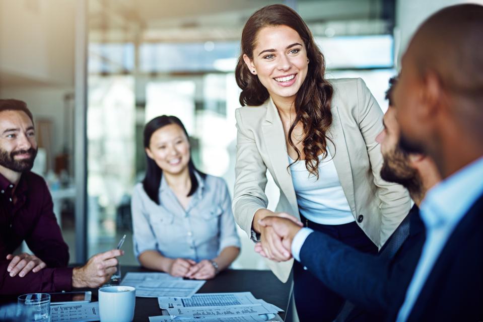 Professional taking initiative by introducing herself during a business meeting, demonstrating leadership, confidence, networking, and career growth.